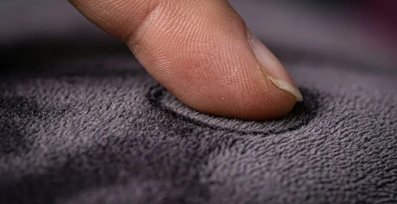 Gros plan macro sur des doigts effleurant délicatement une surface texturée veloutée