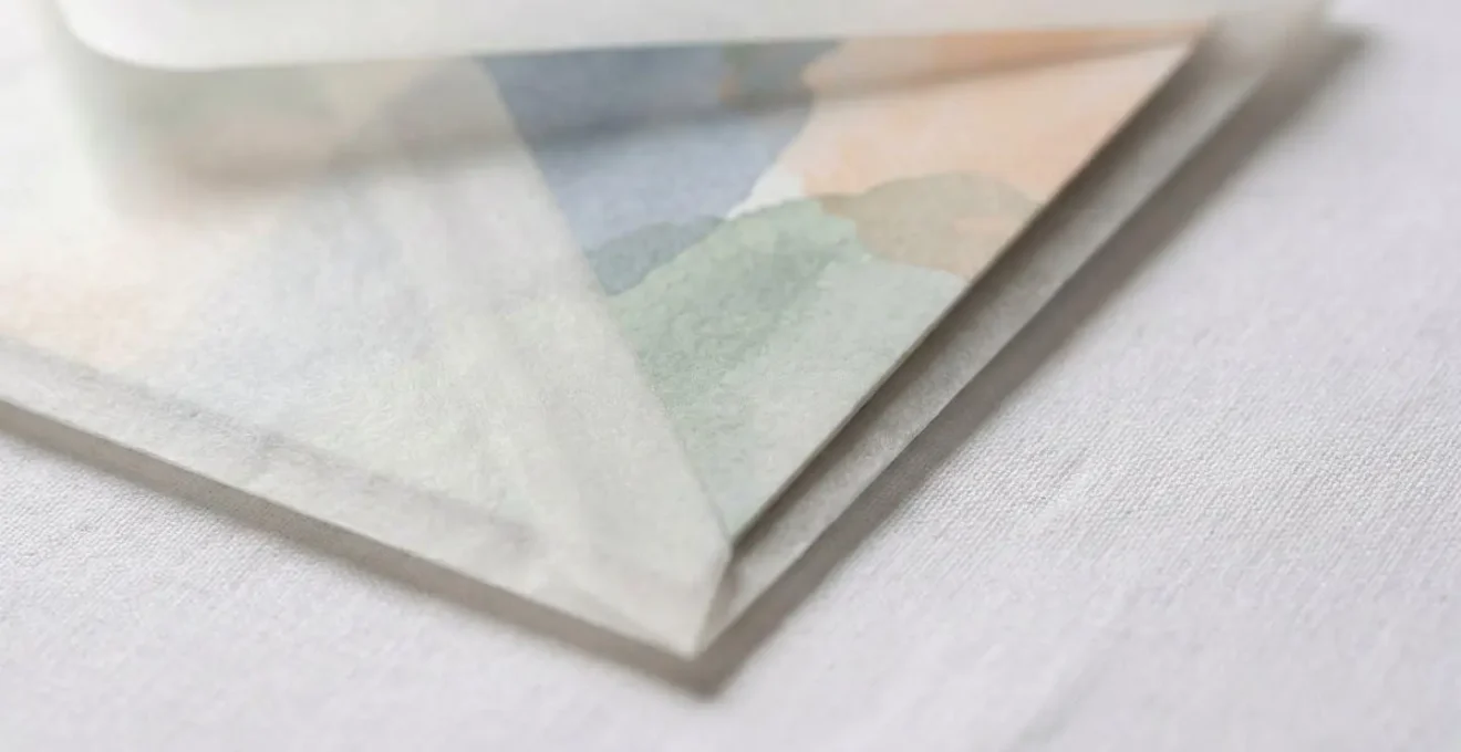 Détail macro d'une carte dans pochette glassine translucide protégeant un tissu blanc